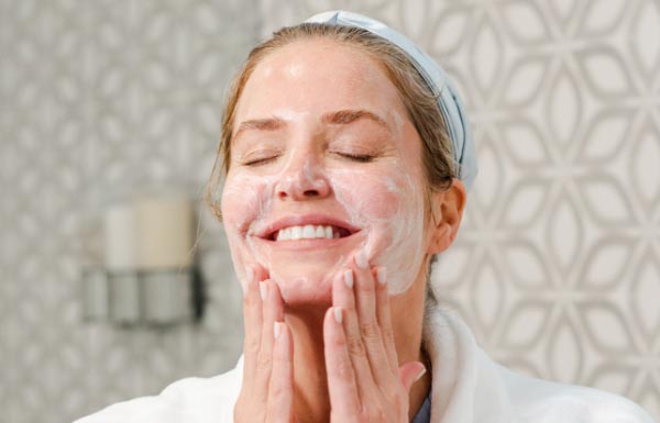 Image of woman washing her face with Neora Double-Cleansing Face Wash..